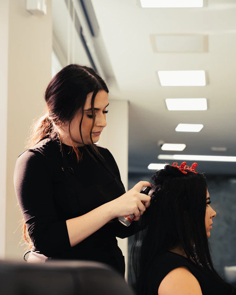Cabeleireira finalizando o cabelo de uma cliente no salão